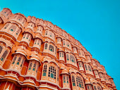 Ornate pink building with many windows against blue sky