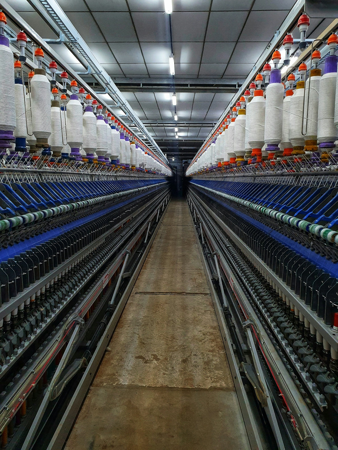 a large room with rows of machines and spools of thread