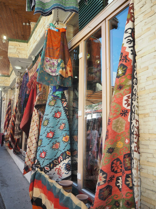 A store front with a variety of colorful scarves hanging from it's windows