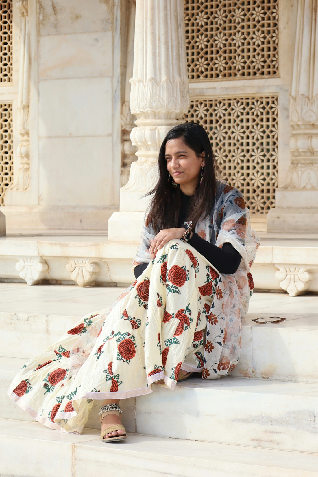 Woman poses on steps of ornate white building.
