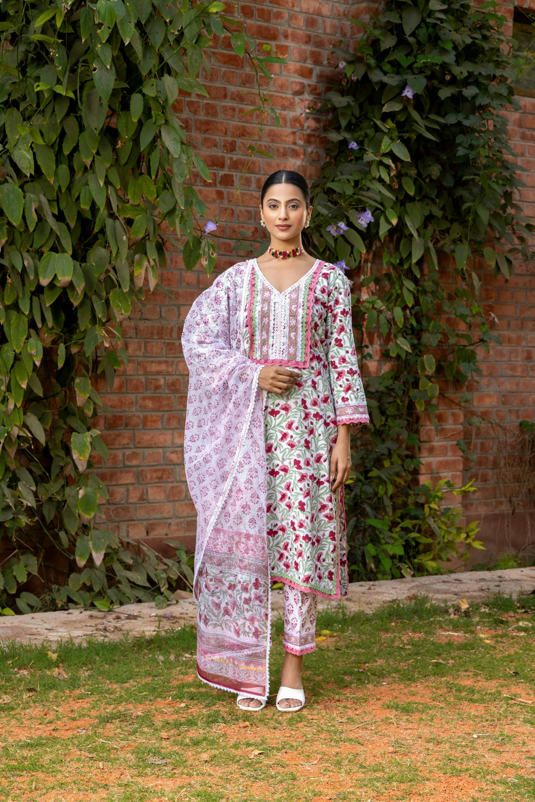 Woman models a floral indian suit with a dupatta.